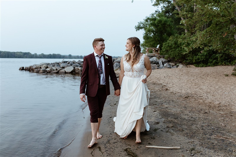 Bride and Groom walking on sandy beach barefoot